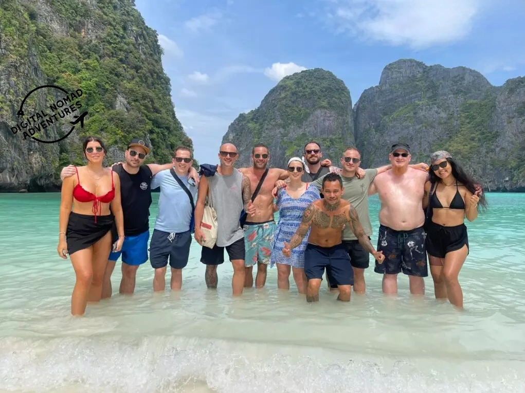 a group of travelers standing in shallow water in a stunning beach in Thailand
